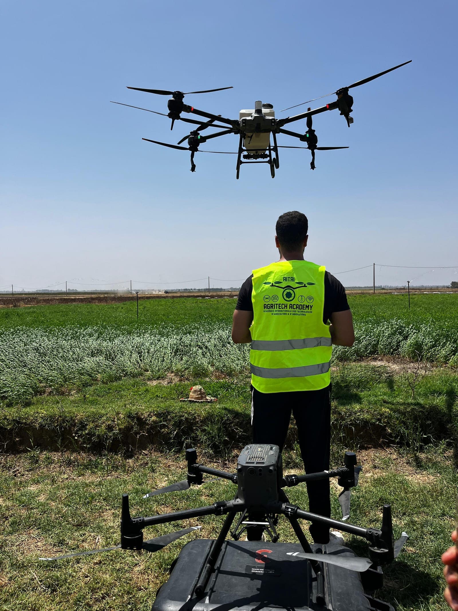 Formateur AgriTech Academy pilotant un drone en plein champ