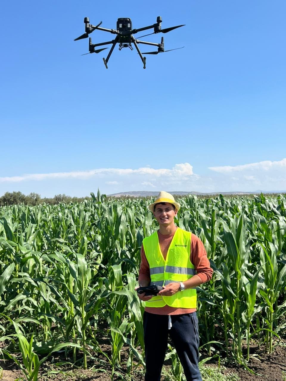 Participant pilotant un drone agricole dans un champ de maïs