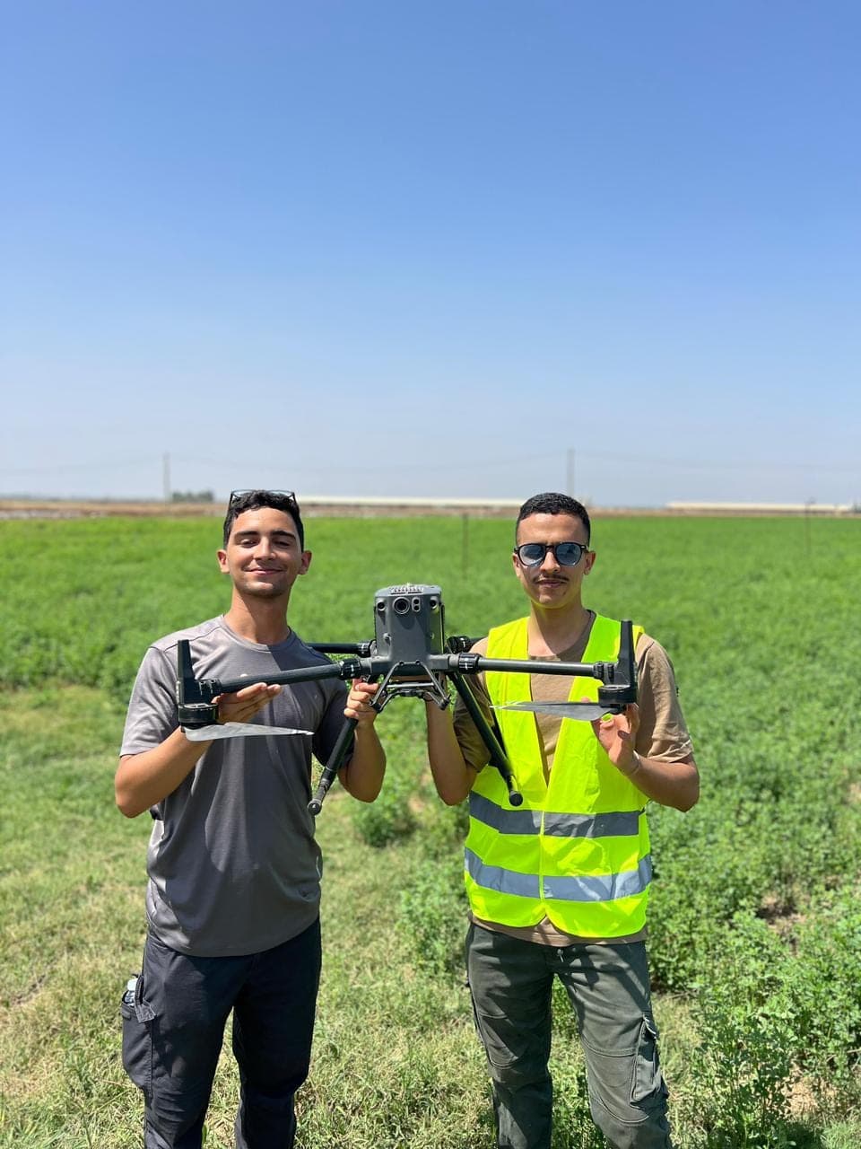 Deux participants tenant un drone agricole dans un champ